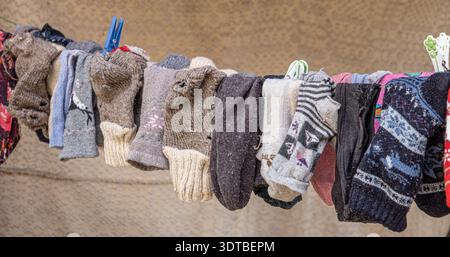 old peasant woolen socks on rope with old wooden hooks with an old carpet in the background Stock Photo