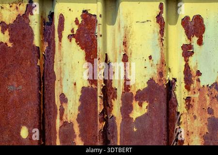 rusted, weathered yellow-painted metal panels. The panels show extensive peeling and flaking, revealing underlying rusty red and brown layers. Stock Photo