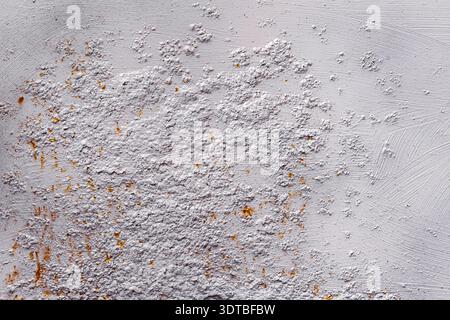 This photograph depicts a textured, white-painted metallic wall with a rough, gritty surface shaped patches of orange rust, giving the image an indust Stock Photo