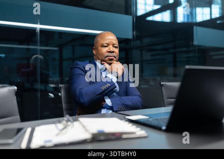 Thoughtful mature black businessman looking at laptop screen in office Stock Photo