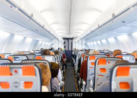 Air travel. Interior of airplane cabin with seated passengers during flight Stock Photo