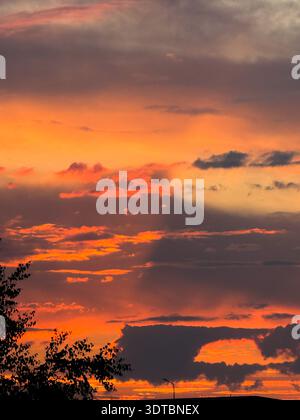 Fiery orange sunset sky with dark clouds Stock Photo