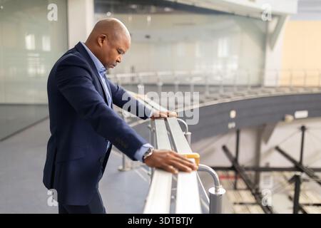 Thoughtful mature black businessman leaning on balcony railing in modern office Stock Photo