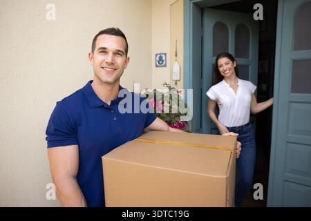 Portrait of deliveryman holding large parcel box to female client Stock Photo