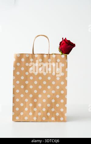 Brown paper bag with white polka dots and red rose on white background Stock Photo
