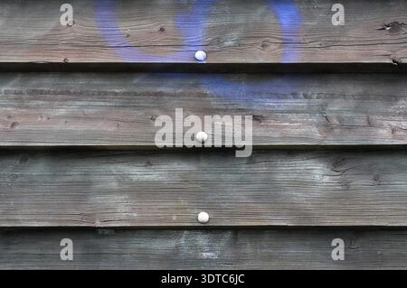 Wooden planks with holes and a blue spot on the wall Stock Photo