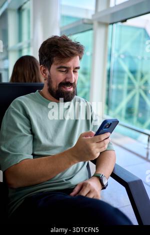 Man using smartphone in airport lounge Stock Photo