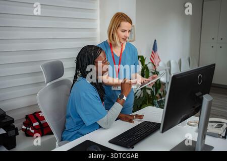 Healthcare professionals collaborating on computer and digital tablet in a clinic Stock Photo