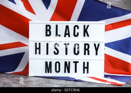 BLACK HISTORY MONTH patriotic scene with signboard and waving flag message UNITED KINGDOM with national colors Festive background with British flag and message board with text Great Britain. Remembrance Day National identity and pride. Stock Photo
