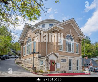 Arkansas, SEP 21 2024 - Historic brick church with stained glass windows and red door stands on corner street under bright blue sky with scattered clo Stock Photo