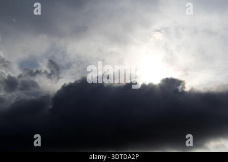 Sun partially hidden behind a dark cloud in a dramatic sky Stock Photo