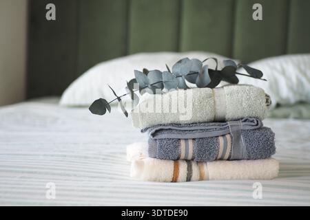 Freshly folded towels on a bed with green background Stock Photo
