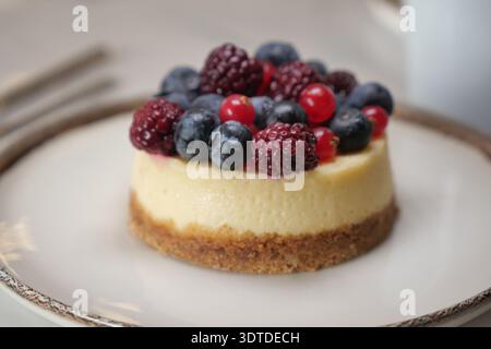 Cheesecake topped with berries sits on a white plate Stock Photo