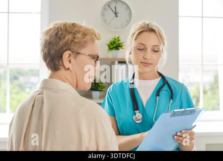 Medical consultation in hospital, conversation of elderly woman and smiling nurse Stock Photo