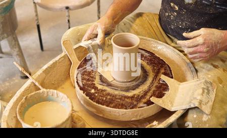 Close-up of potter cutting clay vase from spinning wheel before lifting in ceramic workshop Stock Photo