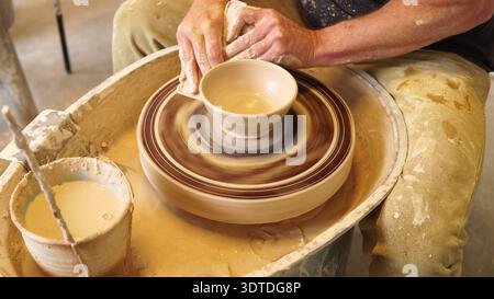 Finished handmade clay bowl spinning on potters wheel in ceramic workshop ready for lifting and drying Stock Photo