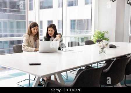 Two multiracial business women engaged with laptop Stock Photo
