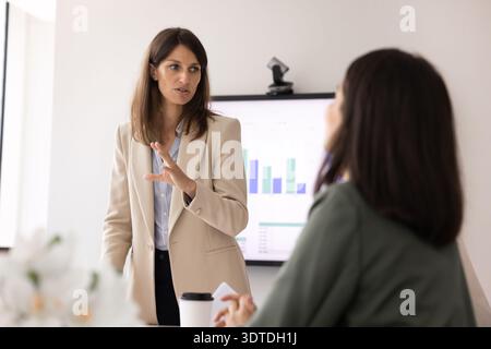 Confident businesswoman standing and speaking during meeting in modern office Stock Photo