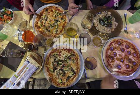 Different pizzas and mussel dishes on a table in a restaurant, Italy Stock Photo