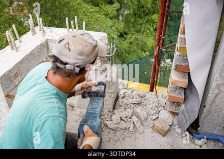Building worker is using electric jackhammer to realign reinforced concrete, removing, destroying, excess on balcony fence of residential building tha Stock Photo