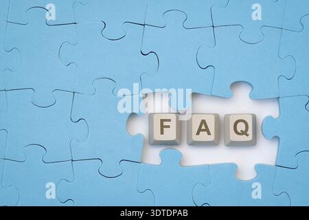 FAQ message on the computer keyboard keys placed among blue puzzle. Acronym faq of frequently asked questions Stock Photo