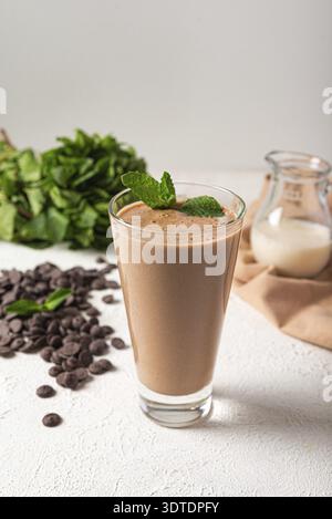 Chocolate protein milkshake in glass white kitchen background. delicious portion chocolate milkshake. healthy protein shake on vegan milk Stock Photo