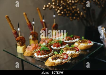 Canapes on a glass table. Canapes of different types of cheese, tartar, salmon, salsa, tomatoes, mozzarella. Luxury catering, Moscow, Russia Stock Photo