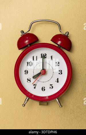 Red alarm clock lying on the golden metal background Stock Photo