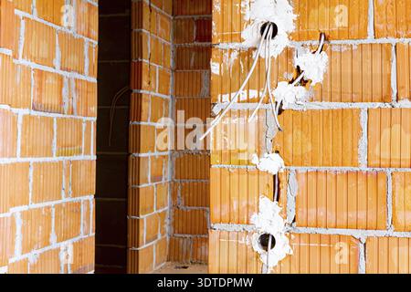 Exposed electrical sockets with the top covers removed for installation of the wiring on the wall with blocks of building under construction Stock Photo