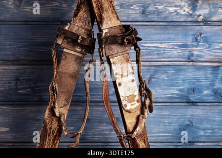 Antique wooden skis with leather strap bindings against a blue wooden background Stock Photo