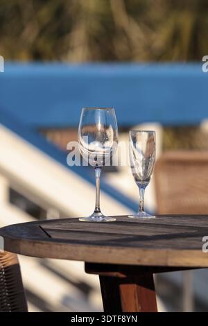 Empty wine glass and champagne flute on a table at the beach in Florida Stock Photo