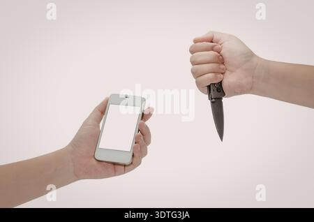 An image depicting a hand holding a smartphone facing a threatening hand with a knife, symbolizing potential danger or cyber threat. Stock Photo