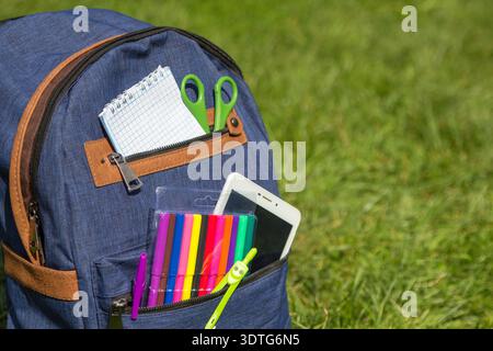 Full School backpack on green grass and nature background Stock Photo