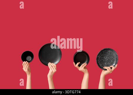 Hands holding empty plates on red background Stock Photo