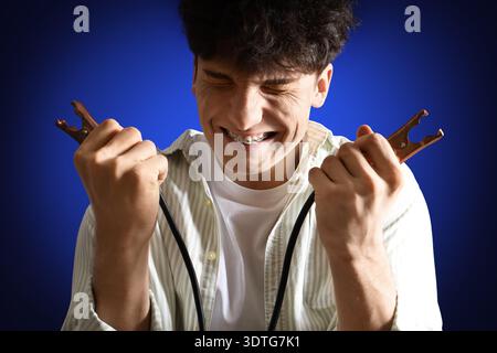 Electrocuted young man with burnt face and jumper cables on dark background, closeup Stock Photo