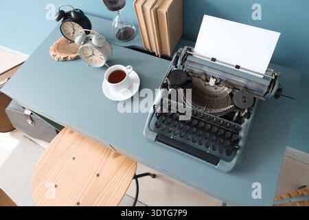 Vintage typewriter with coffee cup, alarm clocks and books on table in office Stock Photo