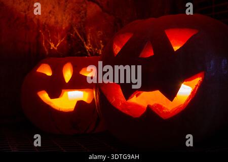 two carved pumpkins in Spider web glow at night Stock Photo