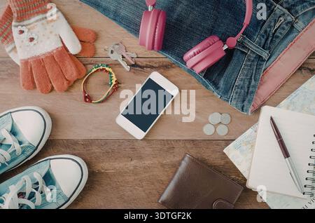 A collection of personal items including a smartphone, shoes, gloves, keys, headphones, jeans, notebook, and other miscellaneous objects. Stock Photo