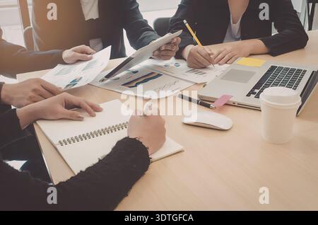 A group of people sitting around a table with laptops and notebooks, collaborating on a project. Stock Photo
