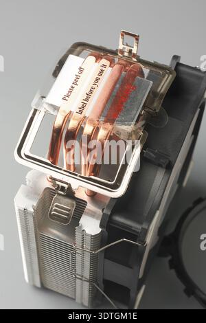 transparent protective film on computer cpu cooler heatsink isolated neutral background, four exposed copper heat pipes and black plastic fan Stock Photo