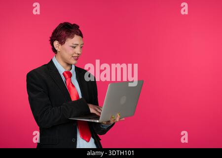 Young professional standing, typing on laptop, using technology Stock Photo