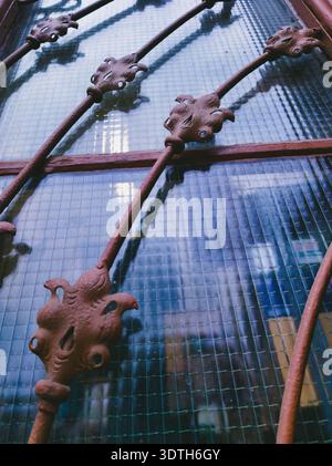 Close-up angled shot of decorative metal scrollwork on an old wooden door with wire-mesh glass, showing authentic textures and architectural heritage Stock Photo