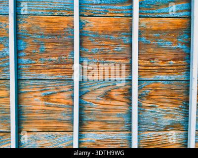 A high-detail shot of white security bars over aged wood featuring vibrant peeling teal paint and orange grain. Perfect for high-quality backgrounds, Stock Photo