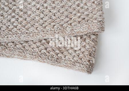Gray wool knitted blanket. The edge of a beige crochet blanket on a white background. Top view, flat lay. Stock Photo