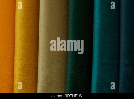Velvet fabric samples in a luxurious palette displaying shades of amber, ochre, charcoal, petrol, and navy. The fabrics are arranged vertically, showc Stock Photo