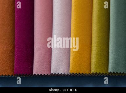 Velvet fabric samples are arranged in a row, showcasing a luxurious color palette. The colors include rich tangerine, deep magenta, soft pink, muted l Stock Photo