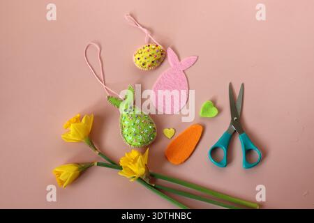 Easter decoration DIY, eggs, rabbits and felt hearts on pink background with copy space. Hand made gift for Easter. Stock Photo