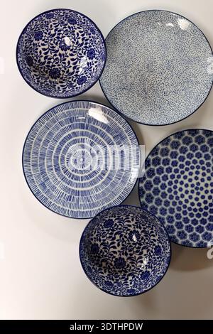 Set of blue ceramic plates and bowls on a light background. Ceramic tableware close up. Stock Photo