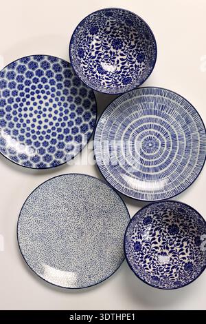 Set of blue ceramic plates and bowls on a light background. Ceramic tableware close up. Stock Photo