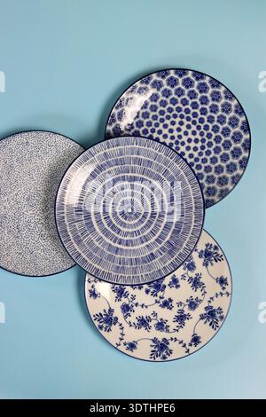 Set of blue ceramic plates and bowls on a light background. Ceramic tableware close up. Stock Photo